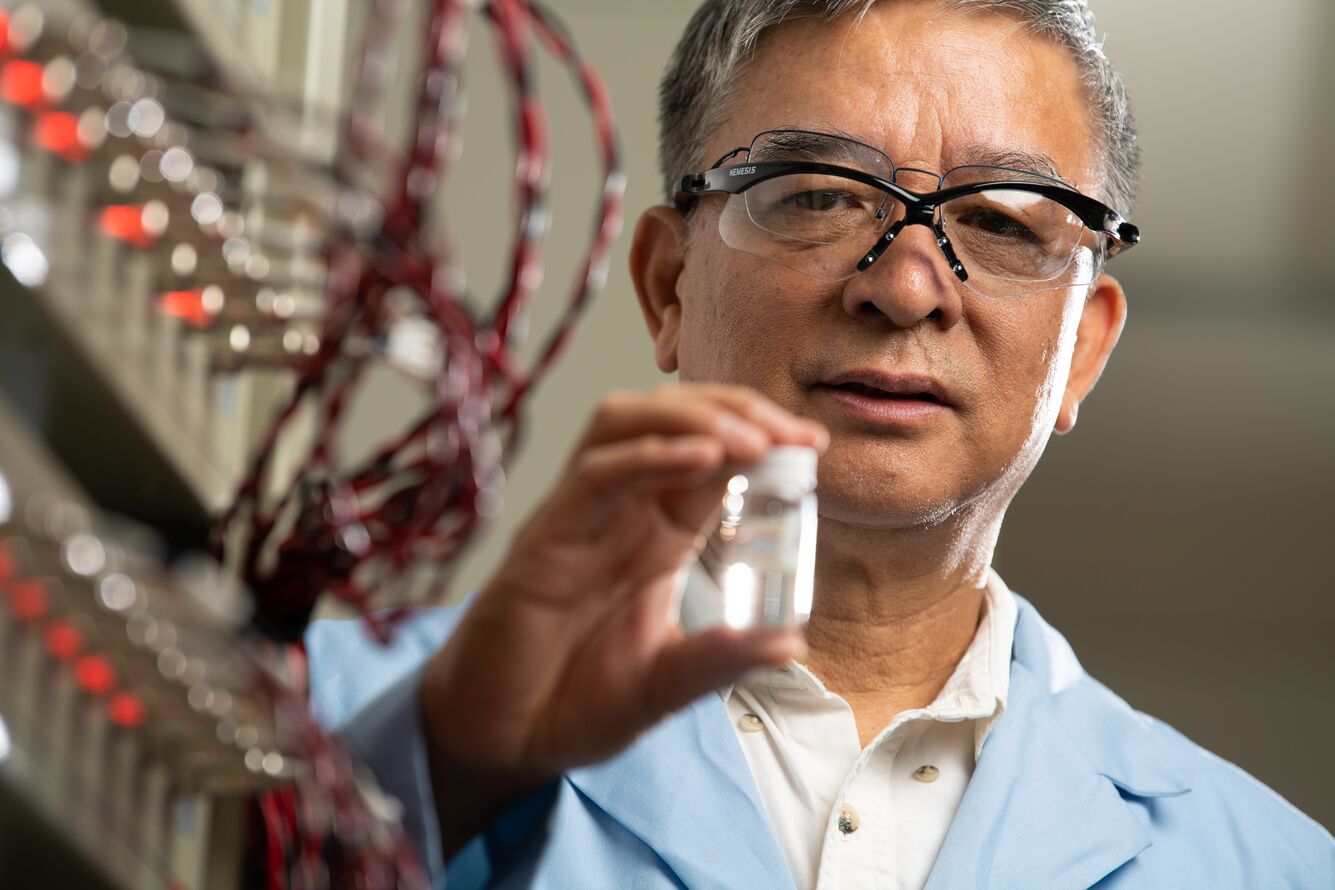 Jason Zhang holding a vial of energy storage material in a laboratory.