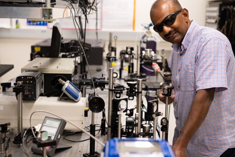 Sivanandan S. Harilal, wearing safety eyewear, standing in front a machine.