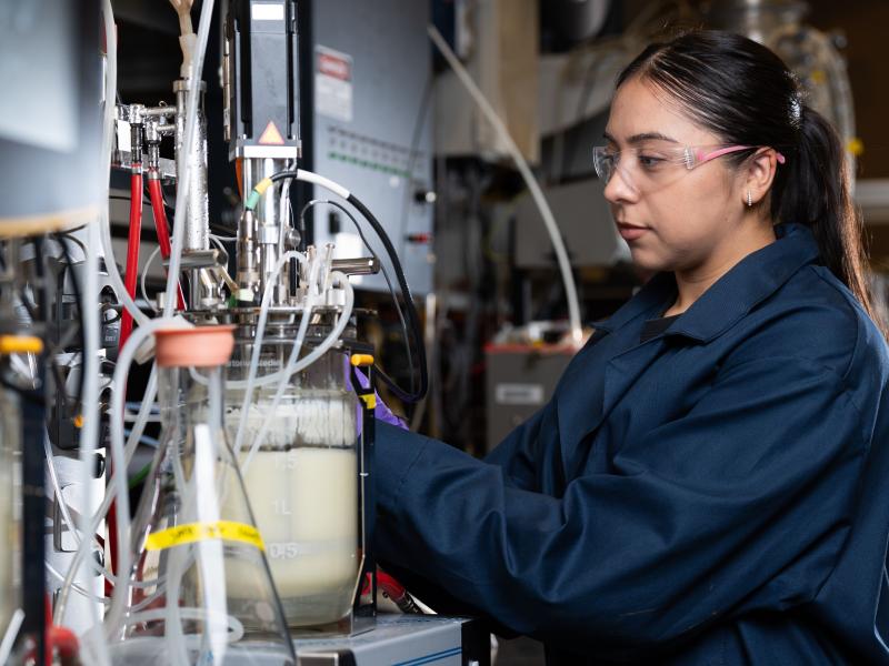 A researcher dressed in safety gear operating machinery